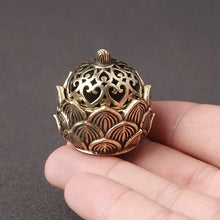 Decorative bronze incense holder held in a hand against a dark background