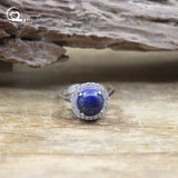 Silver ring with a blue gemstone on a wooden surface