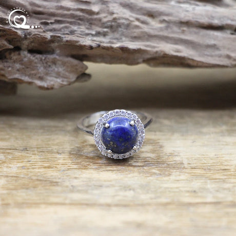 Silver ring with a blue gemstone on a wooden surface