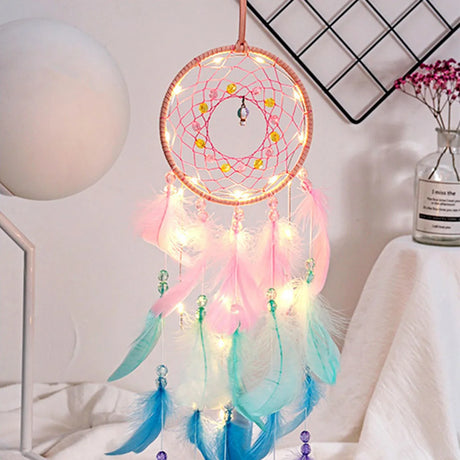 Decorative dreamcatcher with lights and feathers on a white surface.