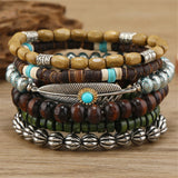 Stack of beaded bracelets with metal accents on a wooden surface