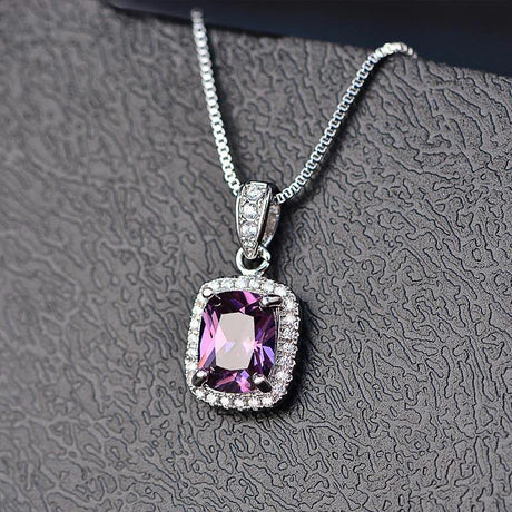 Purple gemstone pendant on a silver chain against a textured gray background