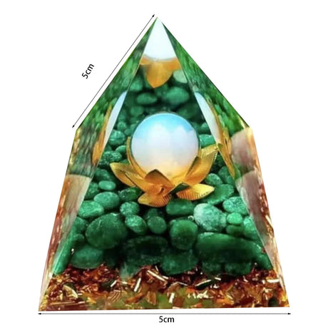Pyramid-shaped object with a pearl and lotus flower design, surrounded by green stones and gold elements.
