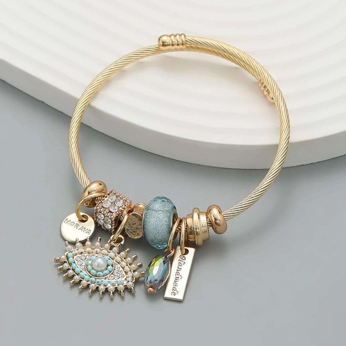 Gold bracelet with various charms on a light gray background