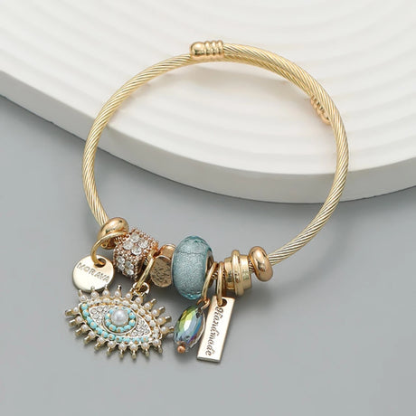 Gold bracelet with various charms on a light gray background