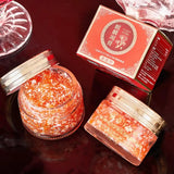 Two jars of red powder with a red box on a dark surface