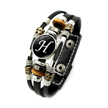 Black leather bracelet with decorative beads and a central black circle with a white 'H' on a white background