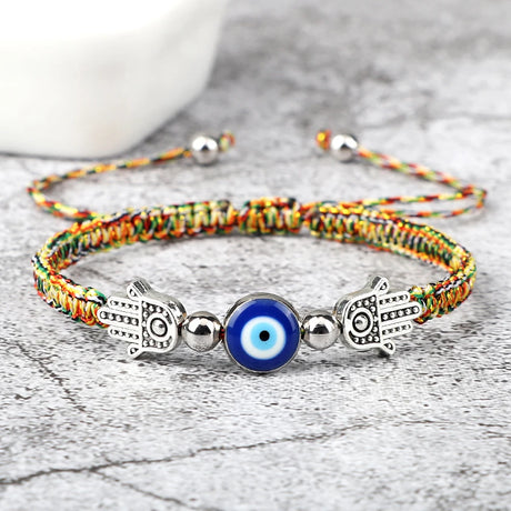Colorful bracelet with Hamsa hand and evil eye charm on a wooden surface