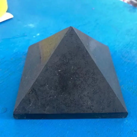 Black pyramid-shaped object on a blue surface