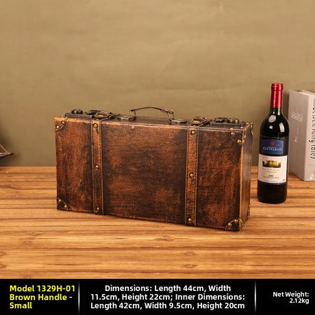 Vintage-style brown suitcase on a wooden surface with a bottle of wine and box in the background.