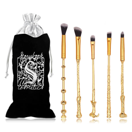 Set of gold makeup brushes with a black drawstring bag featuring a white design on a white background