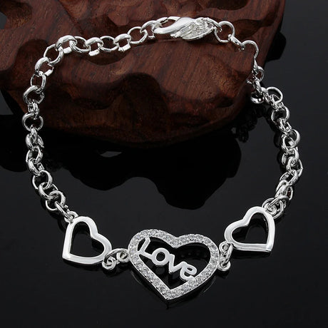 Silver bracelet with heart-shaped charms on a dark background