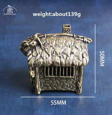 Bronze-colored miniature house figurine with measurements on a blue background