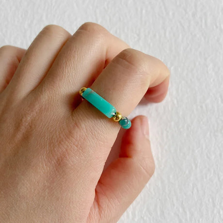 Turquoise beaded ring on a person's finger against a white background