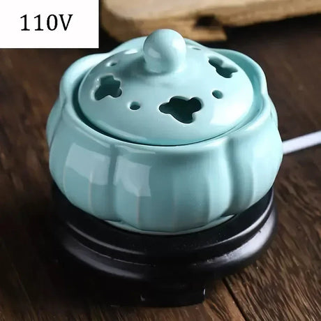 Light blue ceramic incense burner on a wooden surface with '110V' label.