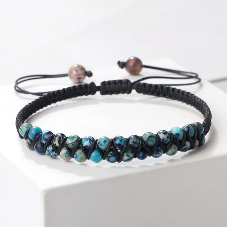 Black braided bracelet with blue beads on a white surface