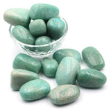 Turquoise stones with a clear glass bowl on a white background