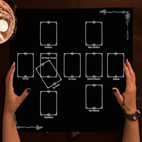 Hands holding tarot cards over a black board with tarot card symbols