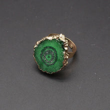 Ring with green spiral design and gold edge on a dark gray background