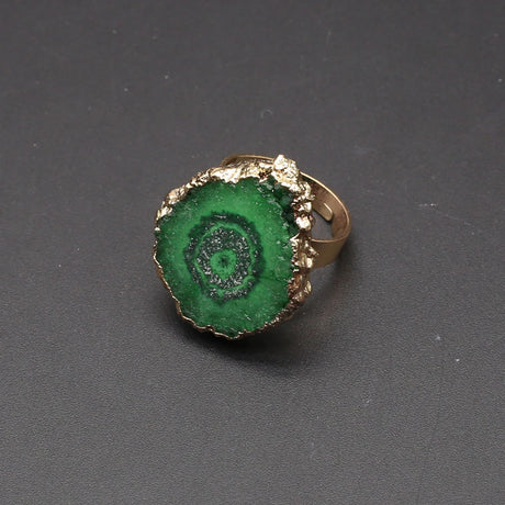 Ring with green spiral design and gold edge on a dark gray background