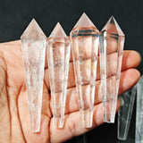 Four crystal points held in a hand against a dark background