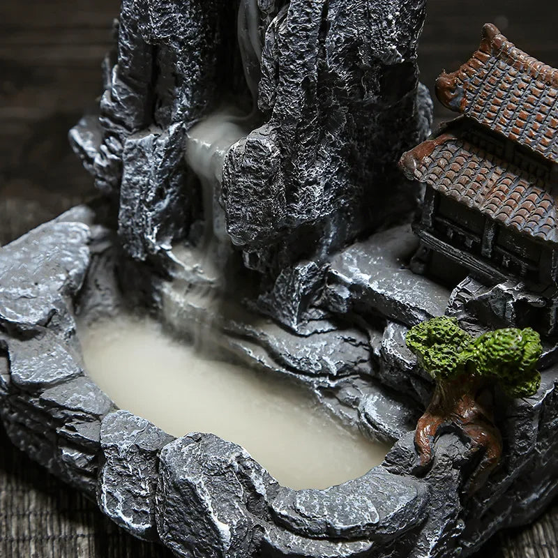 Decorative rock formation with a small building and tree on a dark background