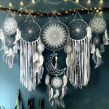 Decorative dreamcatcher with feathers hanging against a dark blue wall.