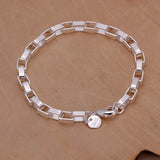 Silver bracelet with a round charm on a beige background