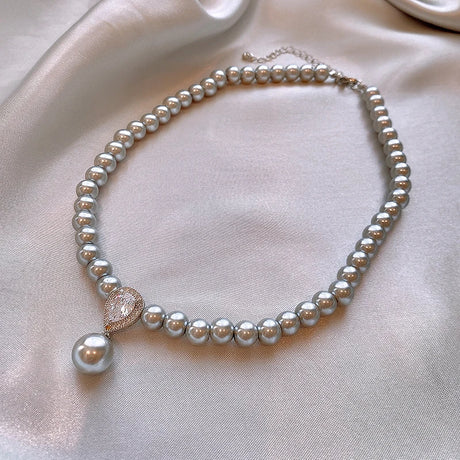 Pearl necklace with a heart-shaped pendant on a light pink fabric background