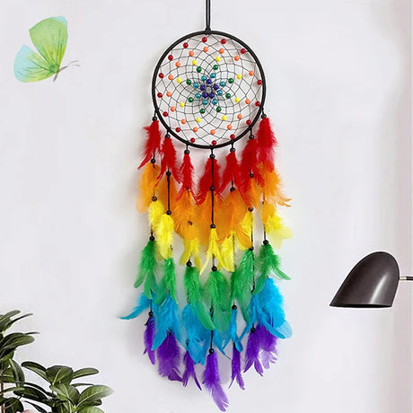 Rainbow-colored dreamcatcher with feathers on a white wall.