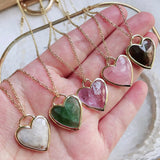 Heart-shaped pendants on gold chains held in a hand