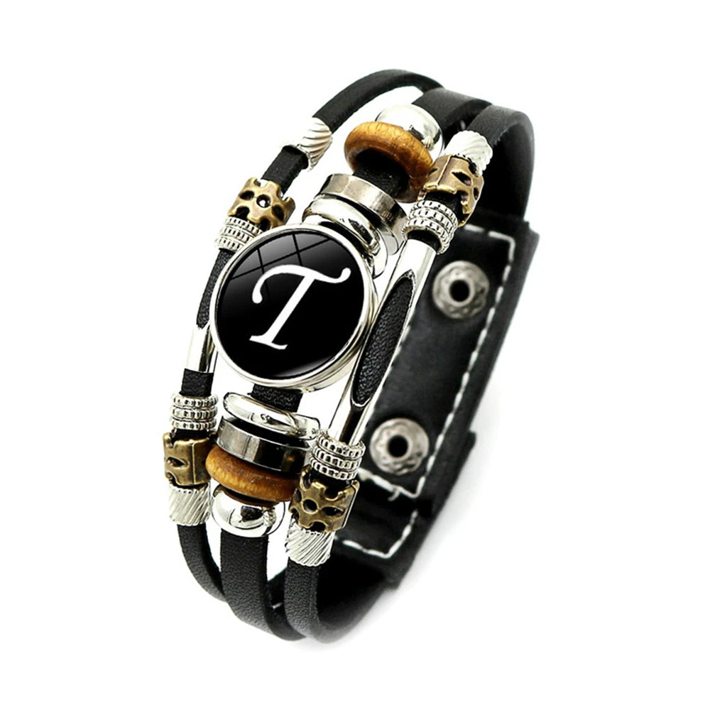 Black leather bracelet with decorative beads and a central black circle with letter 'T'.