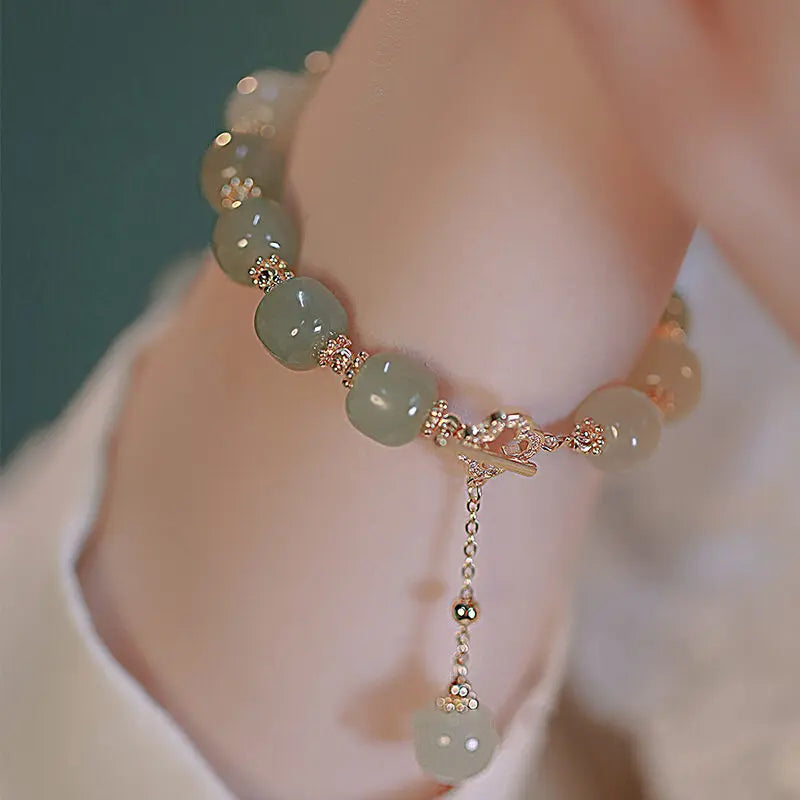 Green beaded bracelet with gold accents on a wrist against a blurred background