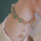 Green beaded bracelet with gold accents on a wrist against a blurred background