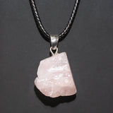 Pink crystal pendant on a black cord against a dark background