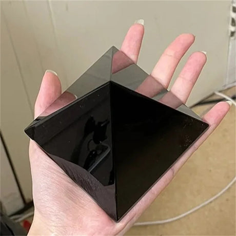 Hand holding a black, futuristic-looking device against a neutral background