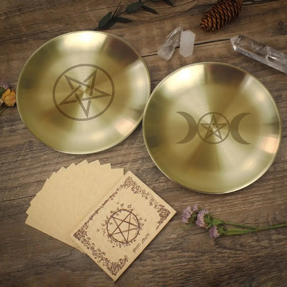 Two gold dishes with star and moon symbols on a wooden surface with cards and crystals.