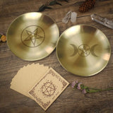 Two gold dishes with star and moon symbols on a wooden surface with cards and crystals.