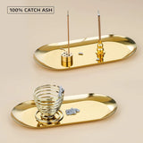 Gold incense holder with two incense sticks on a beige background