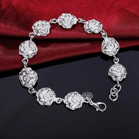 Silver bracelet with intricate designs on a red fabric background