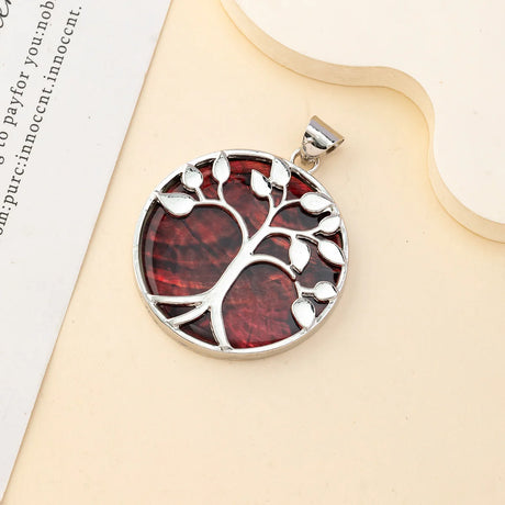 Silver pendant with a red tree design on a beige surface