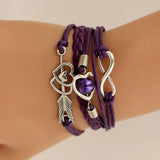 Purple braided bracelet with silver charms on a wrist against a beige background