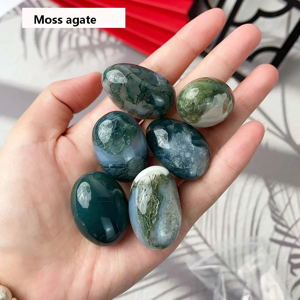 Hand holding moss agate stones with a blurred background