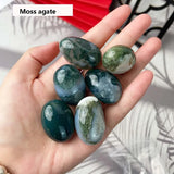 Hand holding moss agate stones with a blurred background