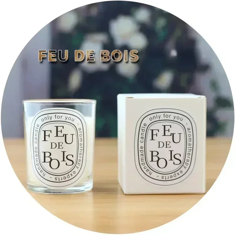 FEU DE BOIS candle and packaging on a wooden surface with a blurred floral background