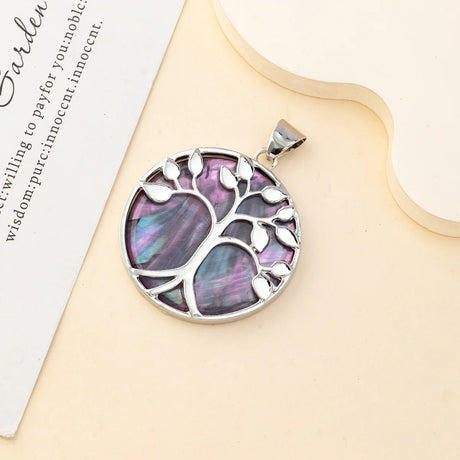 Silver tree of life pendant with purple stone on a beige surface