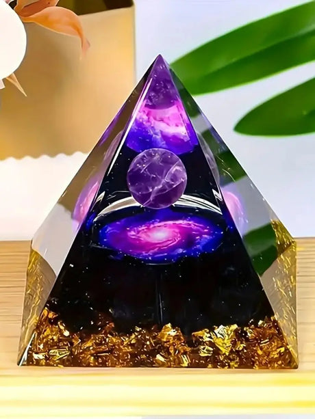 Pyramid-shaped crystal with purple and gold elements on a light background