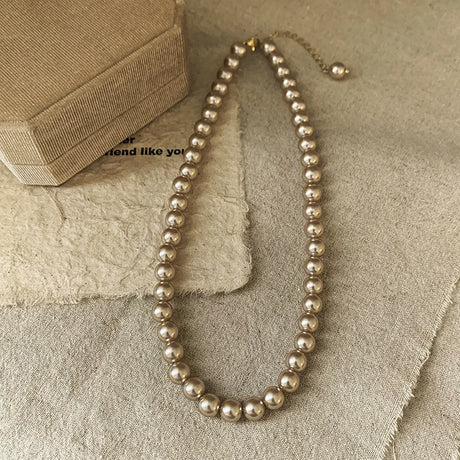 Pearl necklace on a textured beige surface with a box in the background