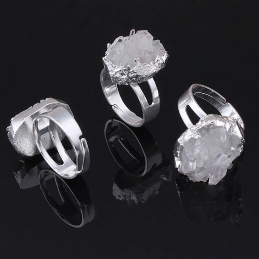 Three silver rings with crystal-like designs on a black background