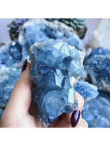 Hand holding a large blue crystal with more crystals in the background